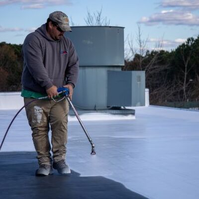 A Roofer Coats a Flat Roof.