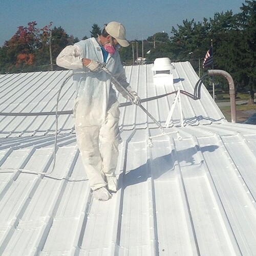 A Contractor Sprays a Commercial Roof Coating.